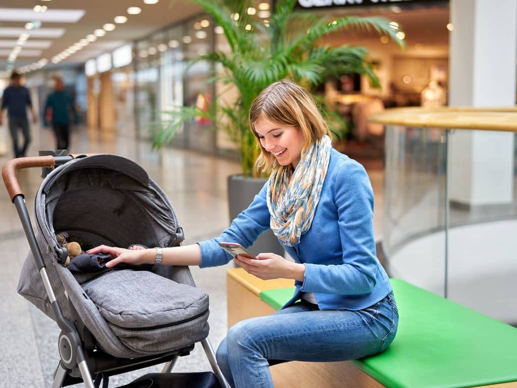 A mum with a pram using a smartphone websites for single parents
