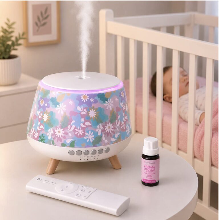 Floral-patterned humidifier on a white round table releasing mist, in a nursery with a sleeping baby in a crib nearby.