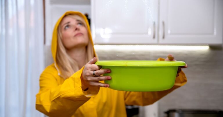 woman catching water into bowl from a leaky roof
